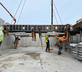 Beam forms with folded legs flown into place using lifting rings.