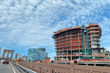 Convex mixed-use building rises next to the Brooklyn Bridge